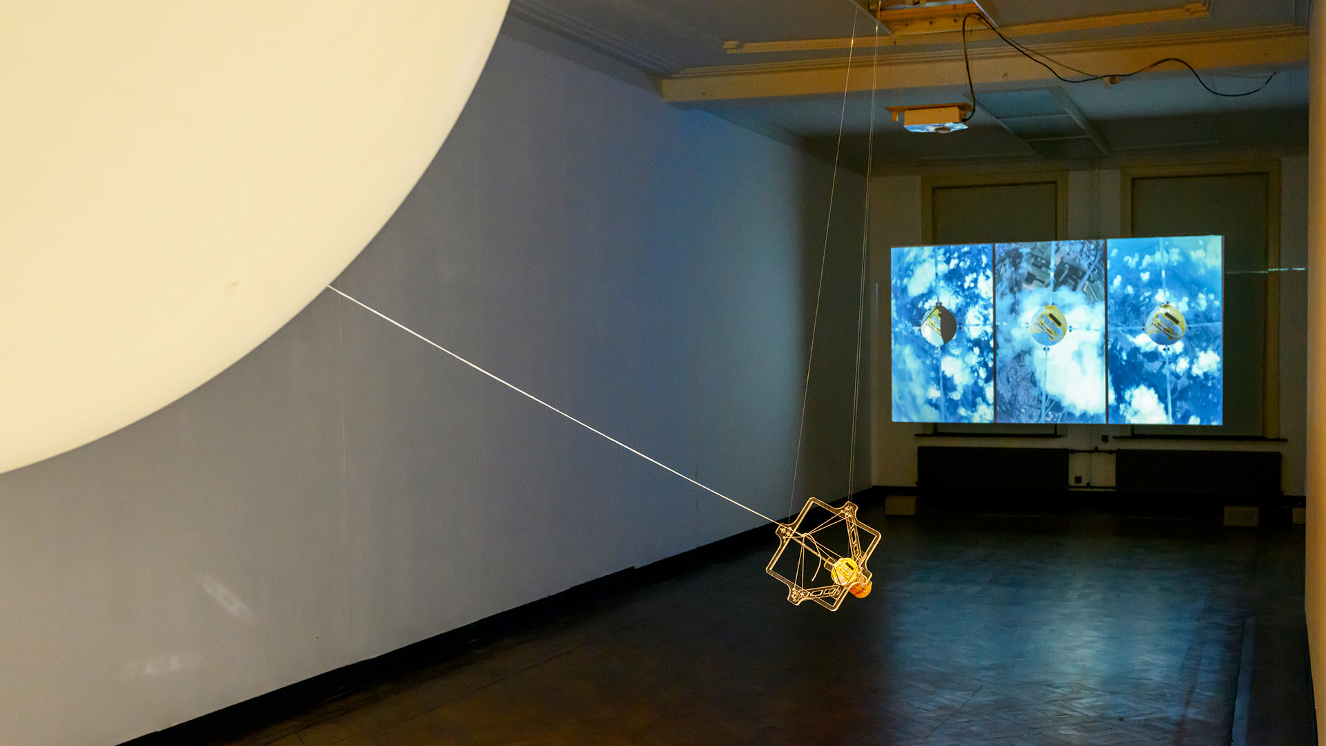 Image of a view of the exhibition depicting a part of an installation and visual media depicting pudding and satellite view.