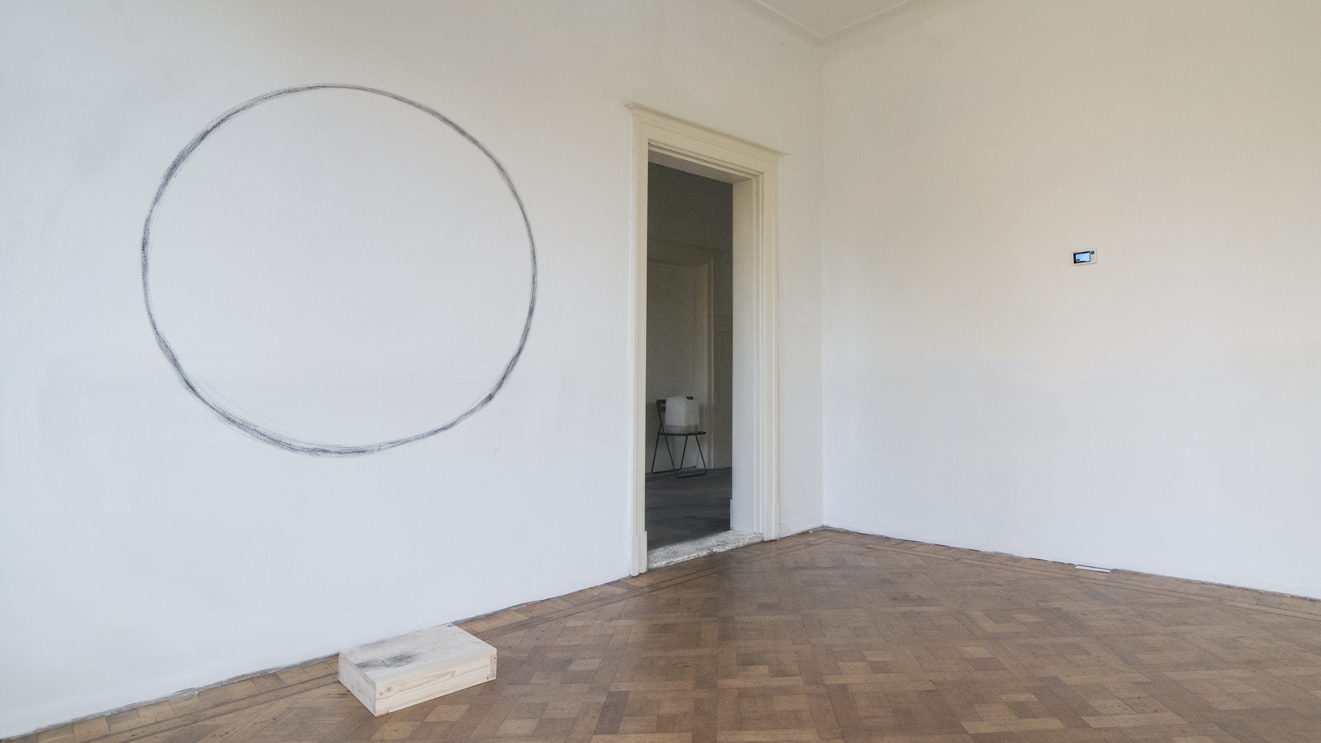 A white room with a big black circle in one wall next to the door.