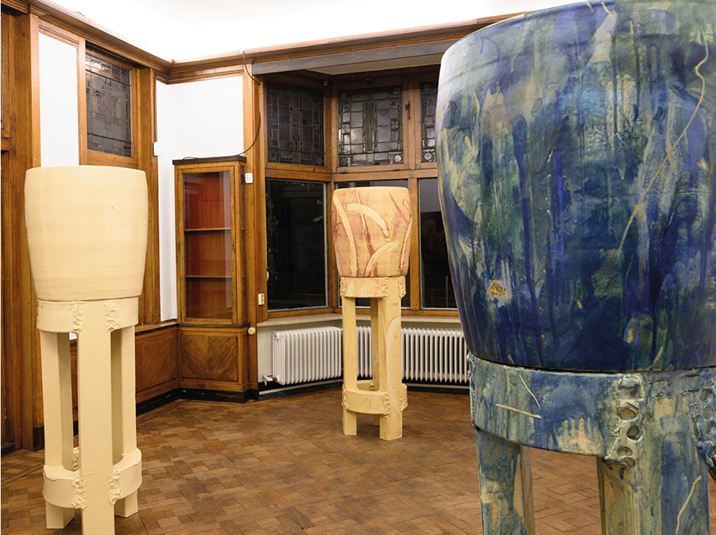 A collection of ceramic towers is displayed in a room, consisting of three distinct works.