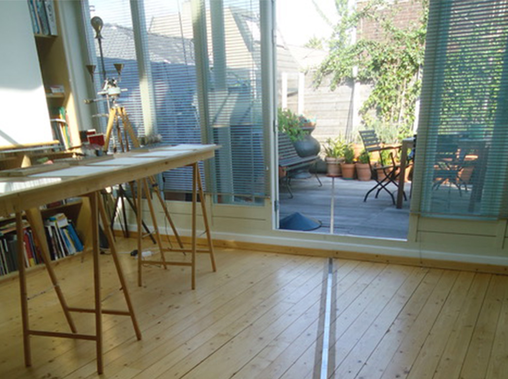 A room with a desk and an open window with a line representing the latitude 51 on the floor.