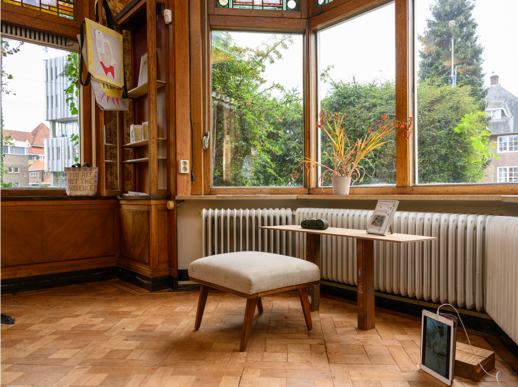 A room with windows, wooden walls and a bench and a table facing the window.