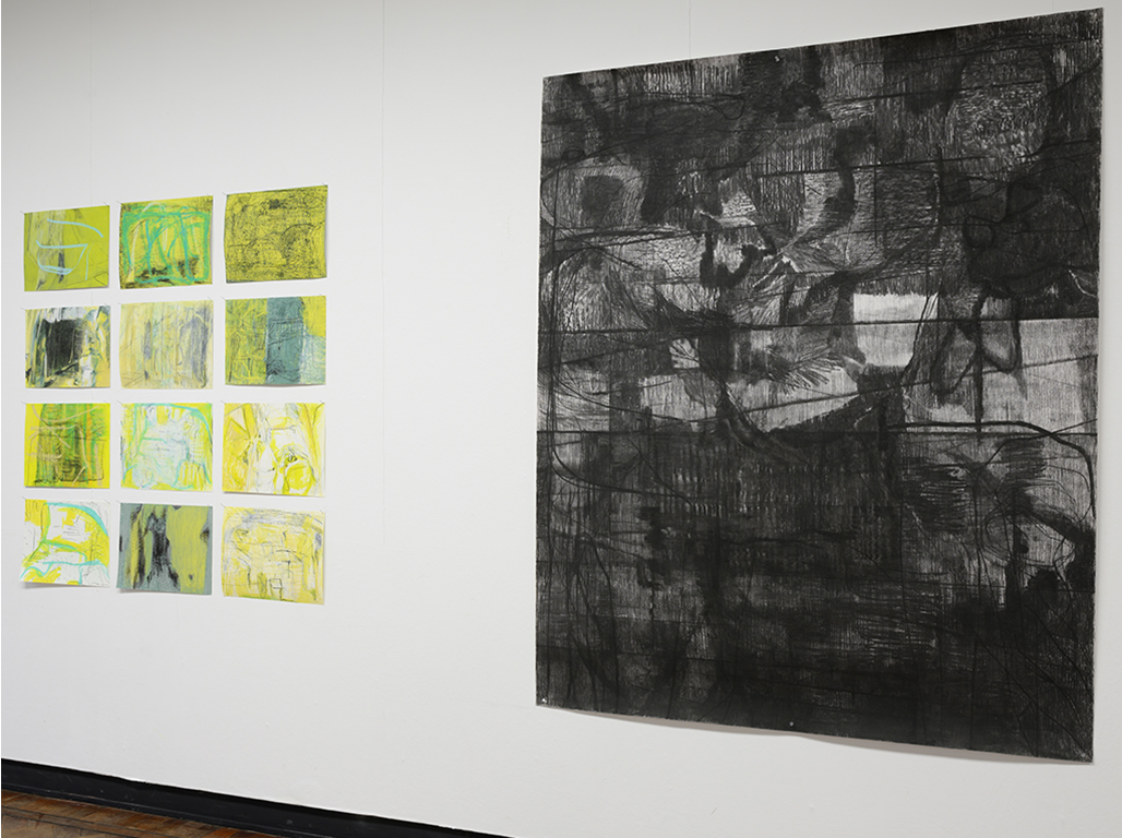 Several colourful art pieces hanging next to a big black and white piece.