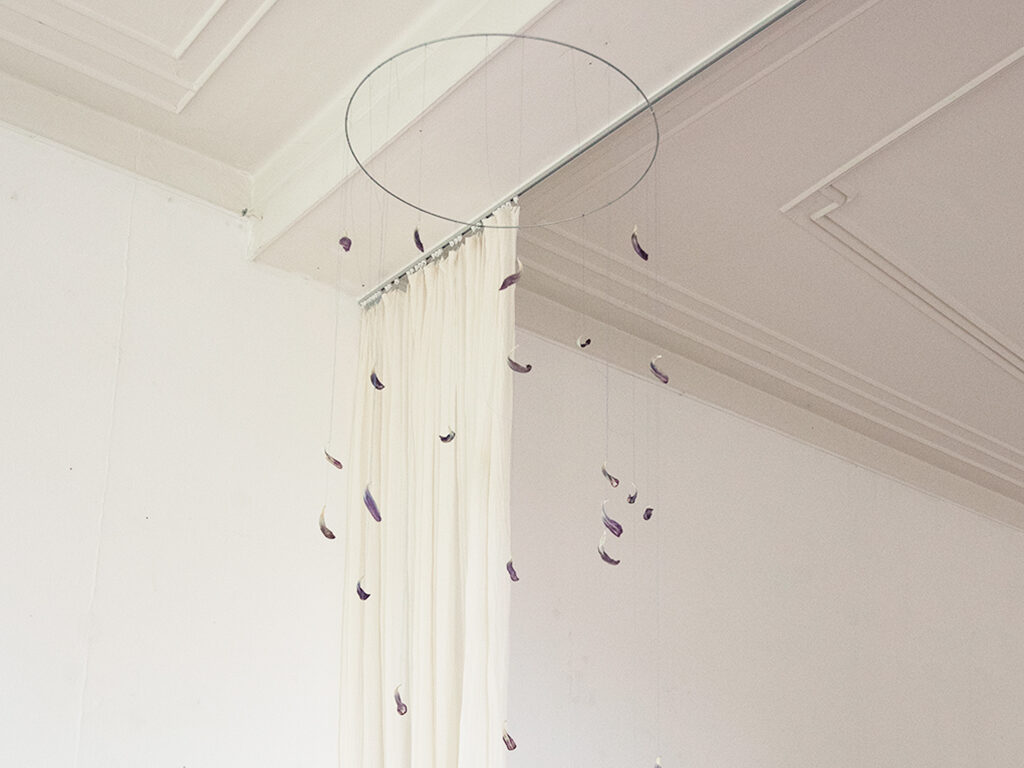 Delicate maquette hanging from the ceiling in a white room.
