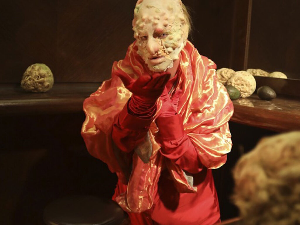A human figure with a exotic skin face dressed with red silk garments.