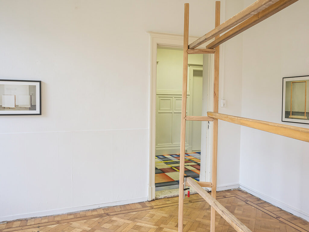 Wooden structure in a corner of the room, and two small frames hanging on the wall.