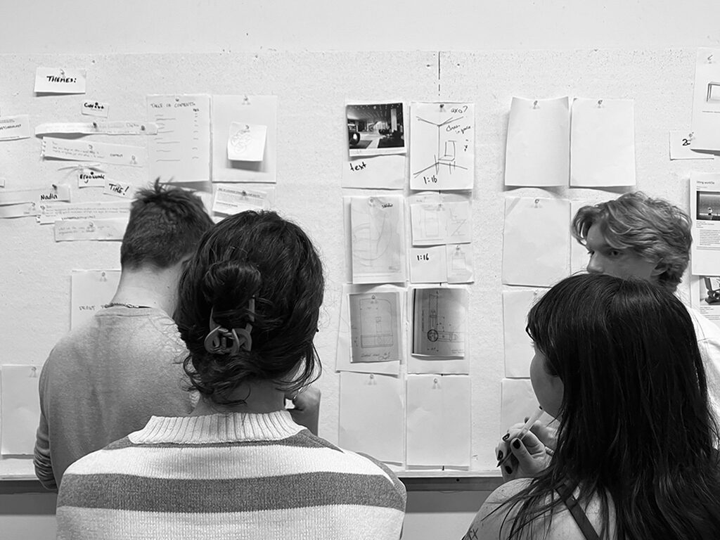 A group of students checking sketches hanging on the wall.