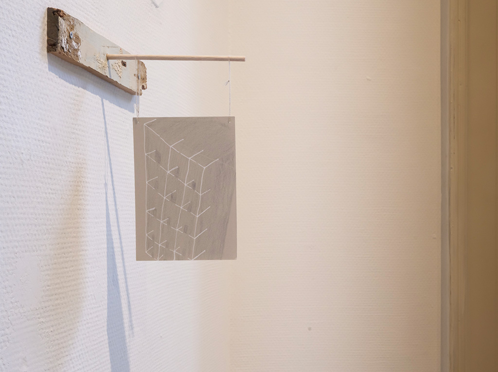 A white sheet of paper suspended by two wires attached to the wall.