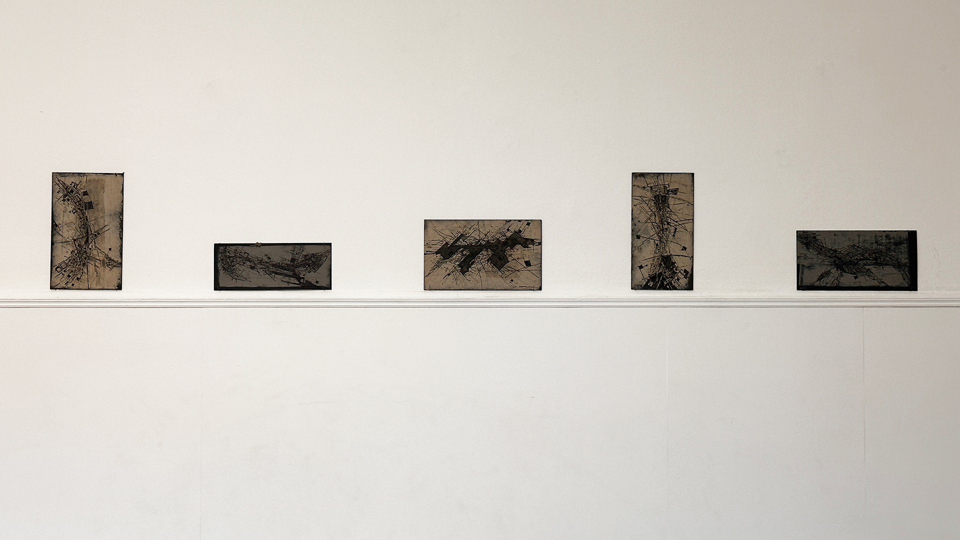 Serie of frames hanging on a white wall.