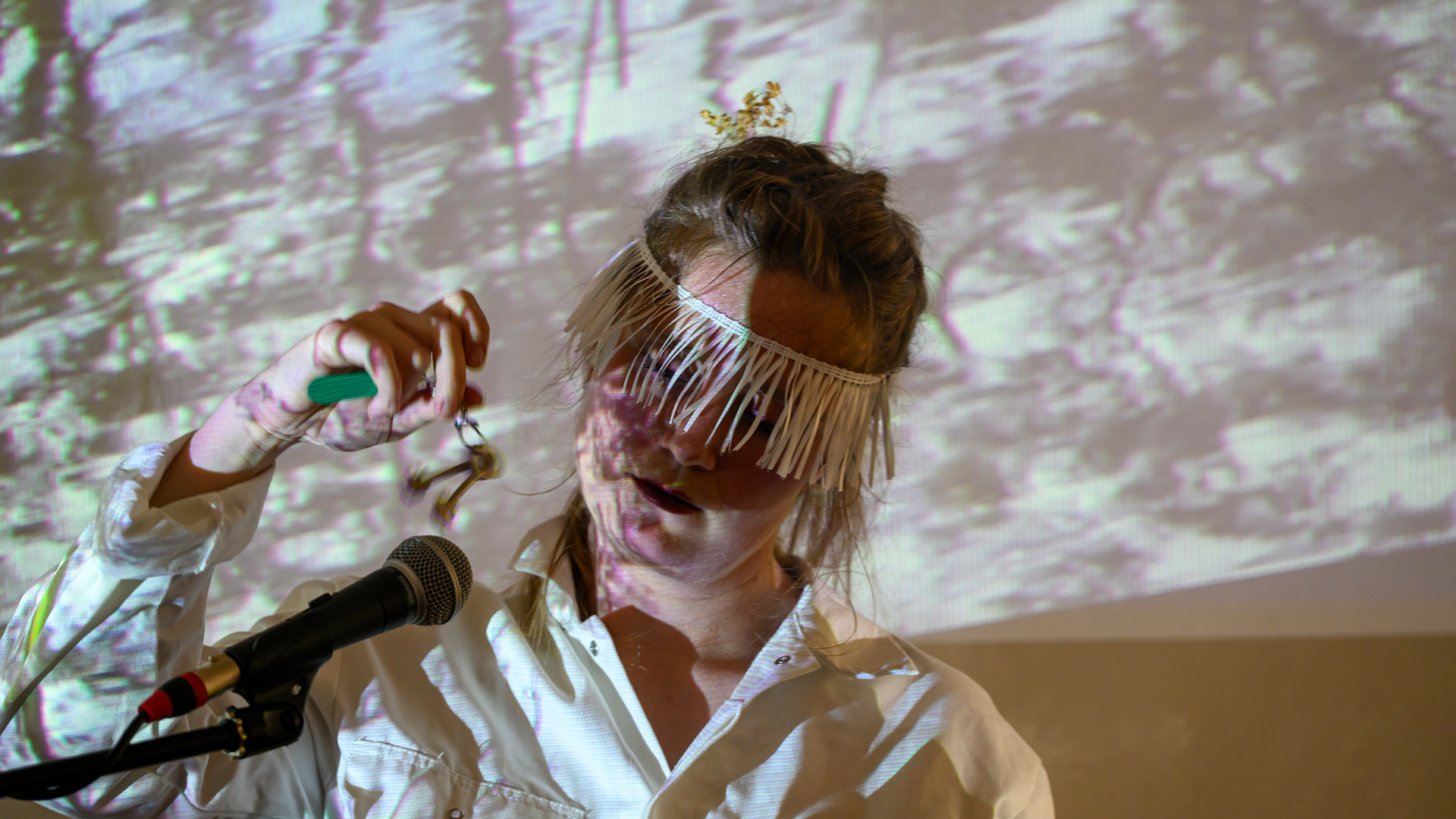 A performer whose face is illuminated with visual projections.