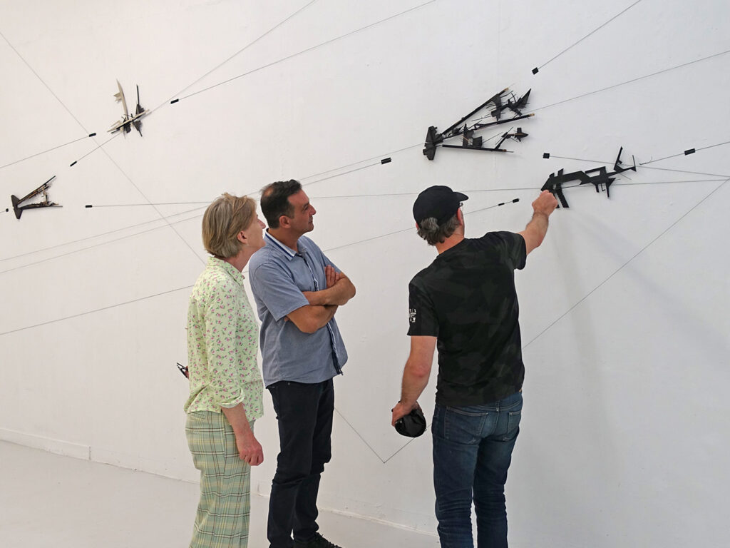 A composition on the wall while the author and some visitors discuss about it.