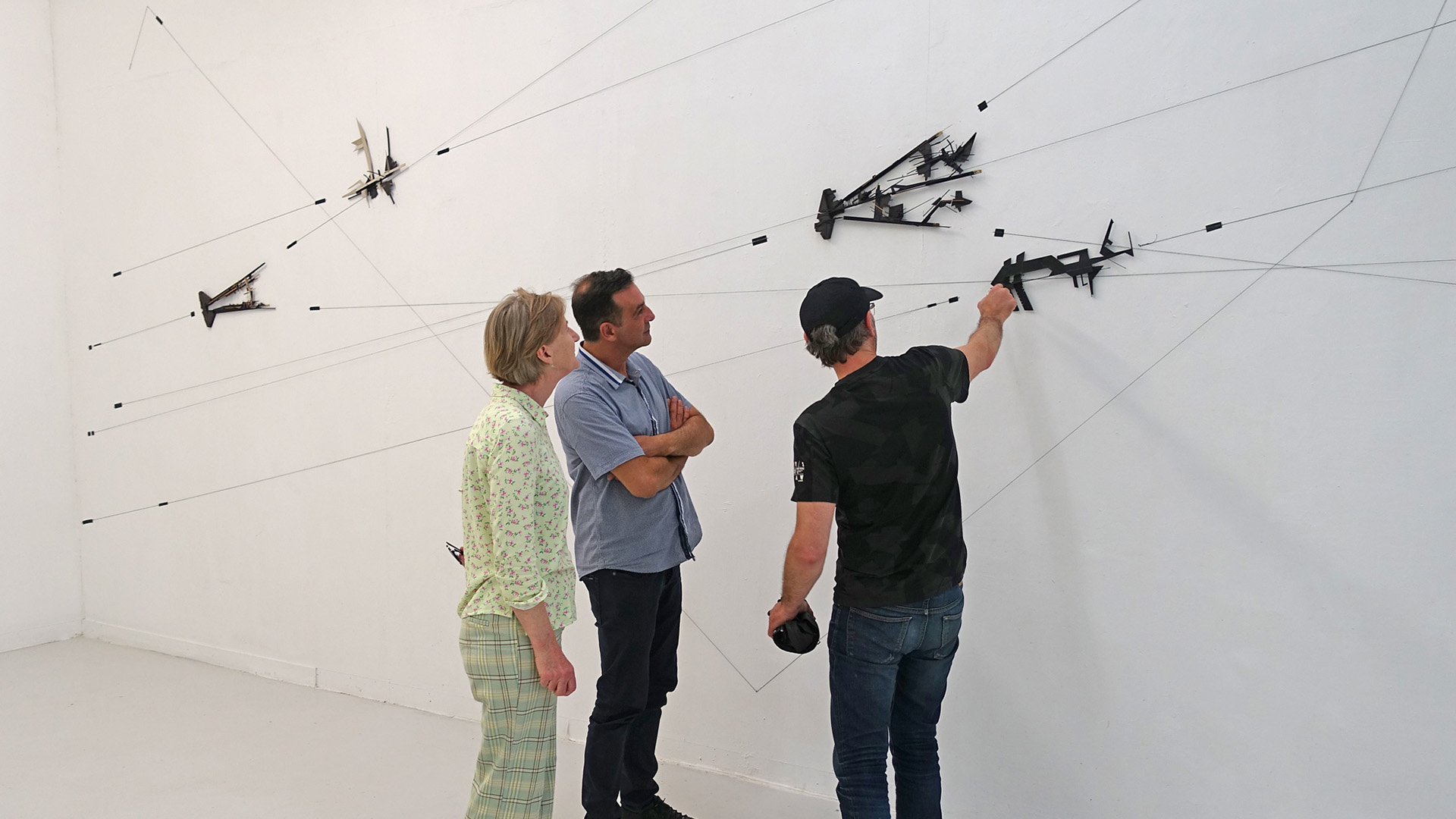 A composition on the wall while the author and some visitors discuss about it.