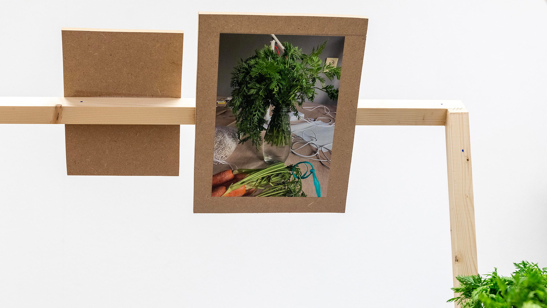 A wooden structure stands in the center of the room, with plants and images arranged on top.