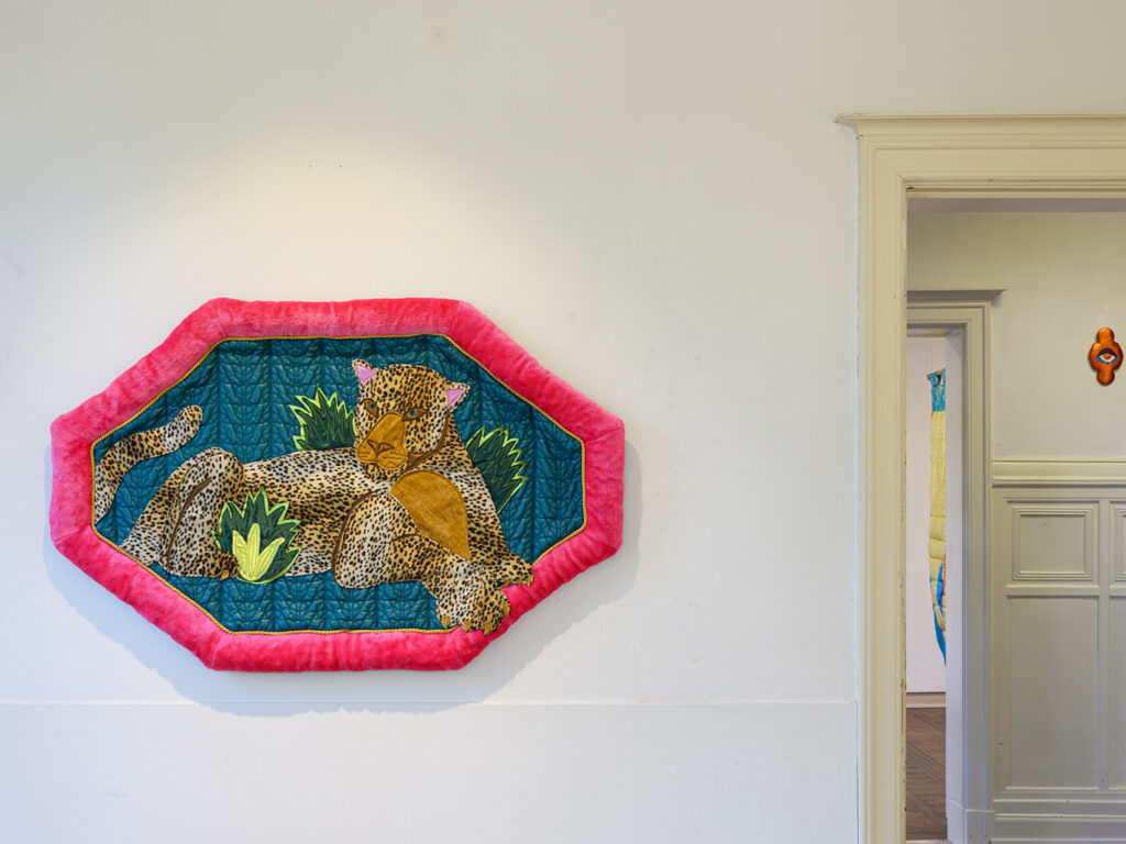 Textile with a represetation of a tiger hanging on a white wall.