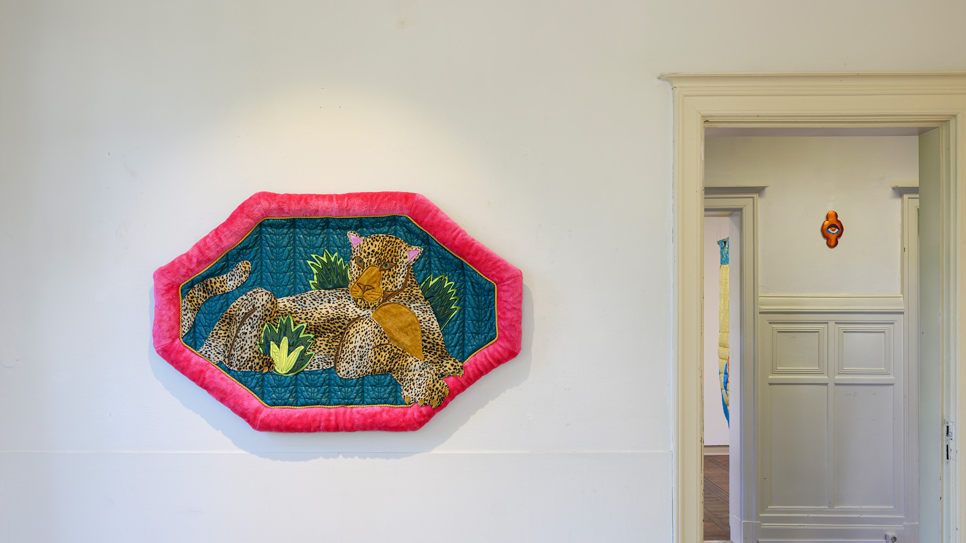 Textile with a represetation of a tiger hanging on a white wall.