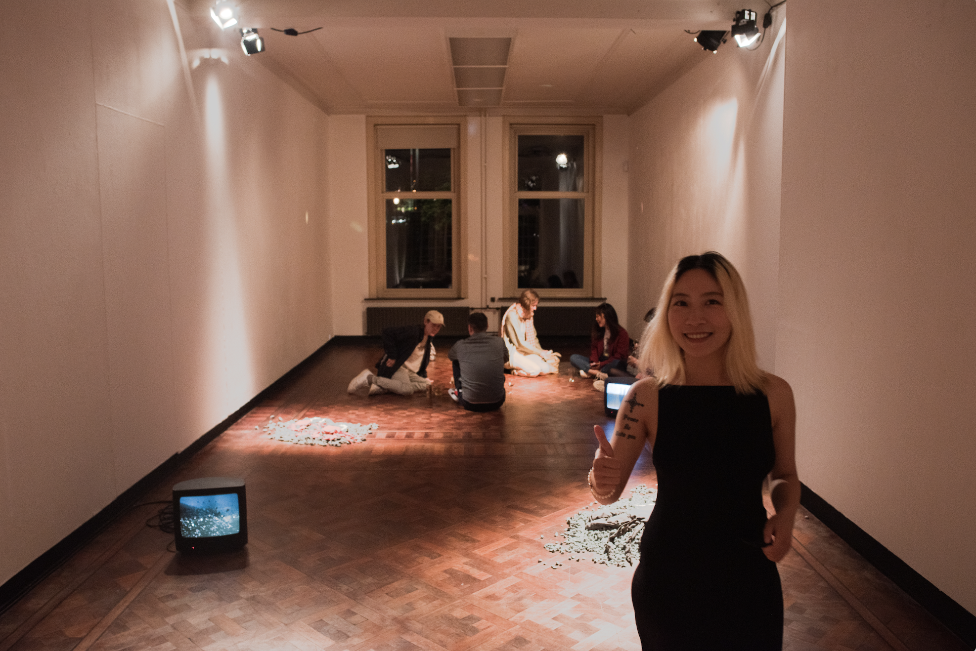 Woman walking up to the camera with a tattoo in between two screens, people sitting in back