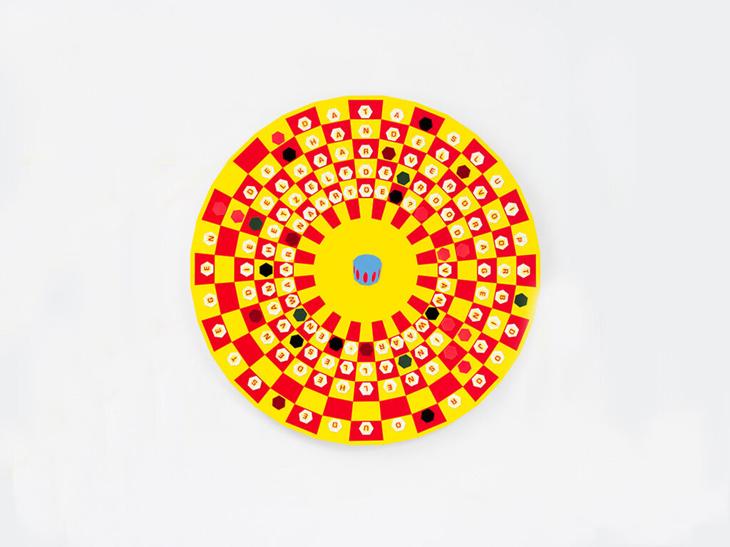 Round bright yellow and orange art sculptural piece mounted on white wall.