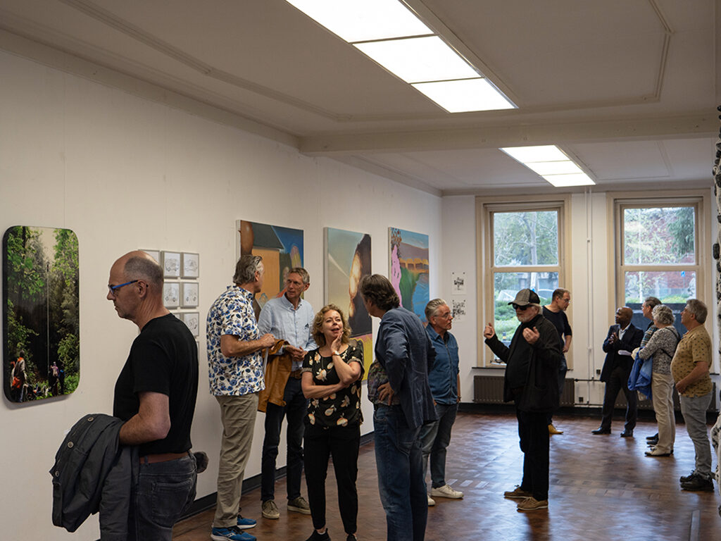 A wide picture of the opening event from exhibition. Visitors are chatting and enjoying the art exhibited.