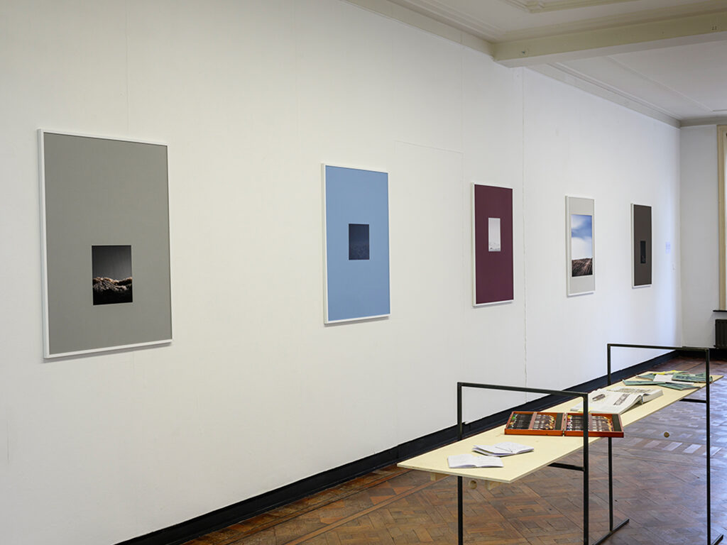 A space with some blue, burgundy and grey frames hanging on the walls.