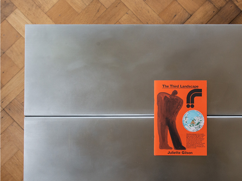 A metal table with a red small book on it.