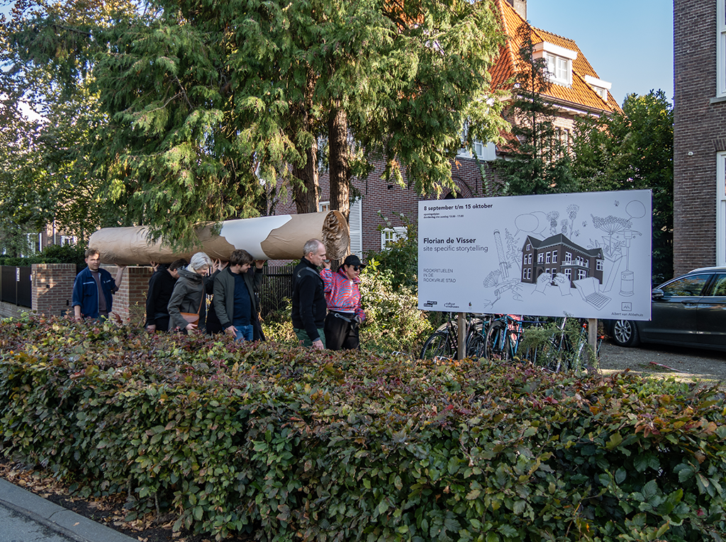 A group of persons walking around the city carrying a big cigar together.