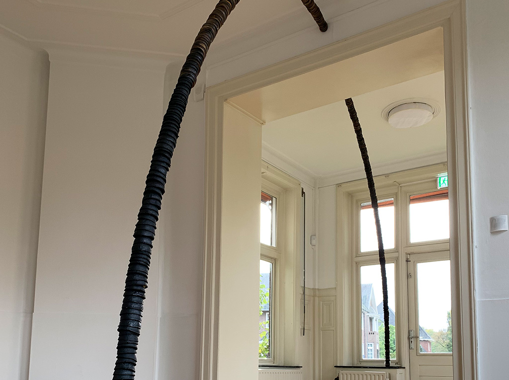 A black tube cuts sharply across a white wall.