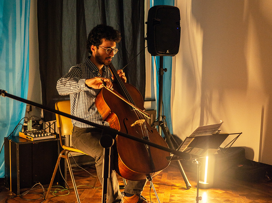 A live musical performance unfolds in a dimly lit white room.