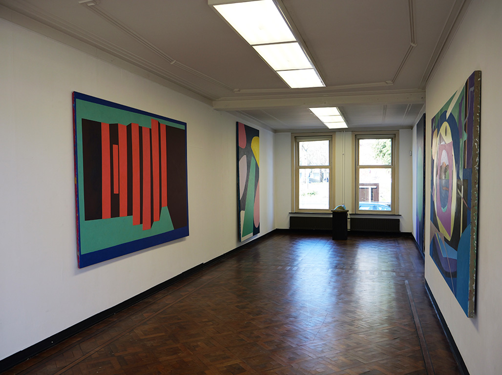 A wide white space with different and colourful frames hanging from the walls.