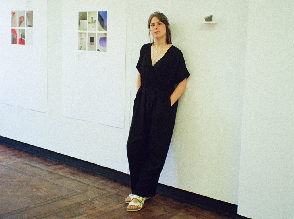 The artist photographed next to her work which hangs from the wall.