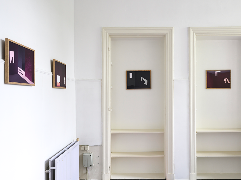 The corner of a room with frames hanging on the walls.
