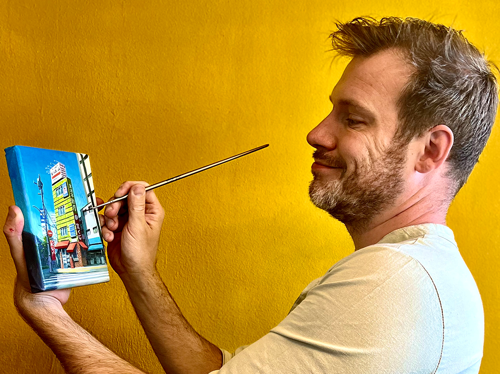 An artist painting on a small canvas.