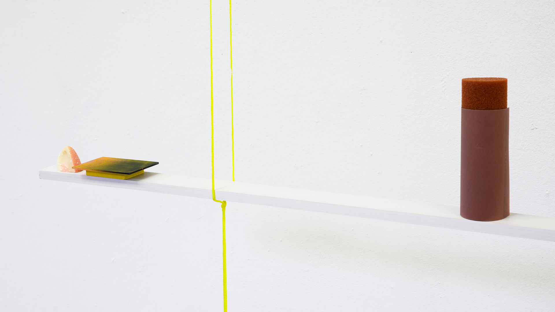 A shelf hanging from the ceiling with two ropes, showcasing an arrangement of small objects.