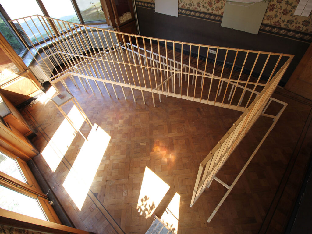 A n installation of wooden geometrical structures built through a sunlit space