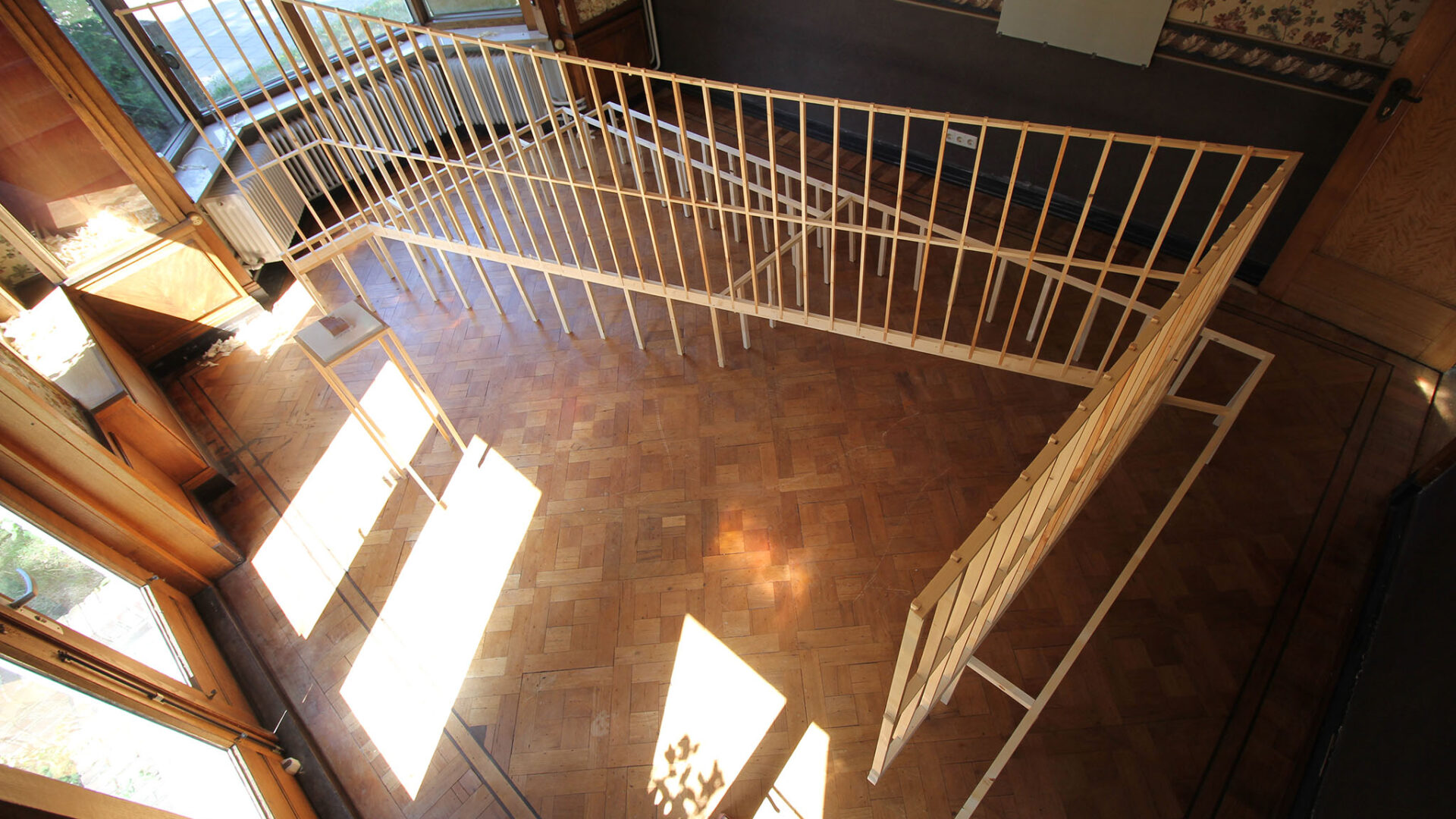A n installation of wooden geometrical structures built through a sunlit space