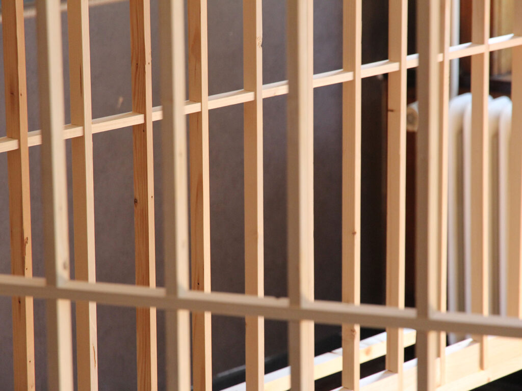 Close up of an installation of wooden geometrical structures built through a sunlit space