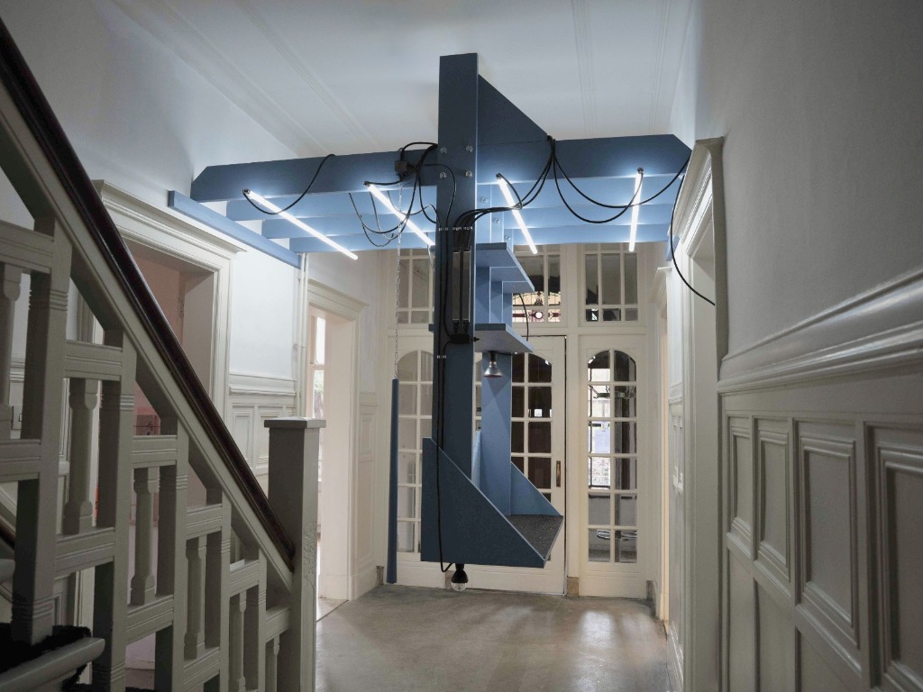 installation of a grey or blue wooden panel with LED lights installed as a counter in the entrace of a space