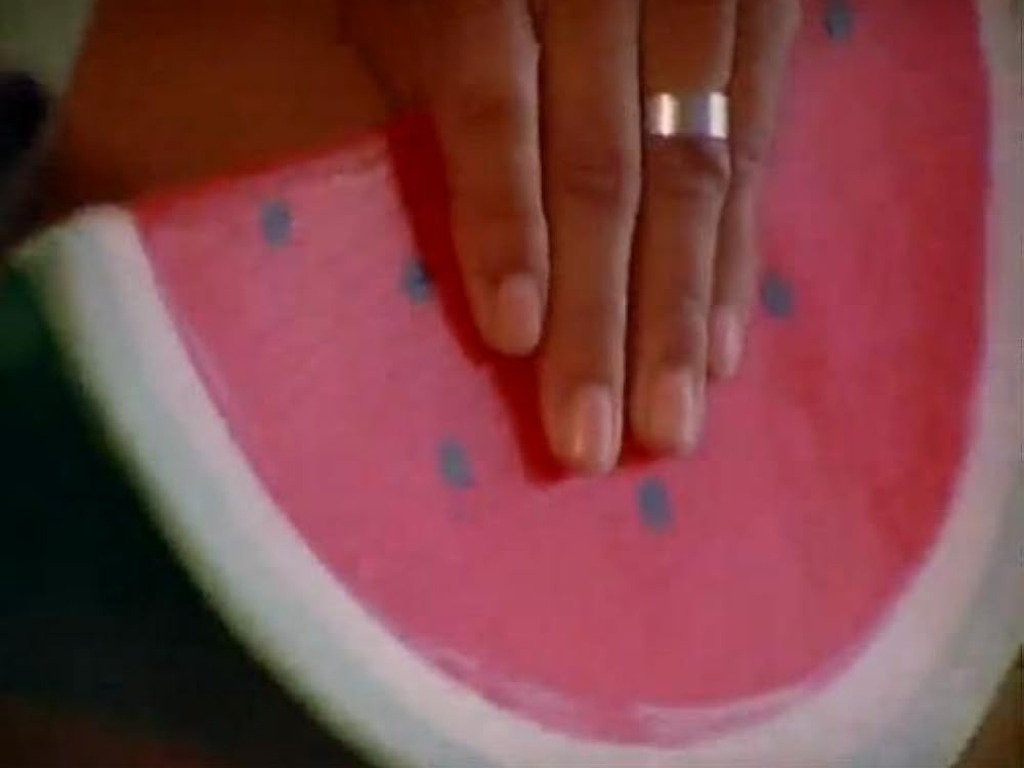 A hand grabbing a watermelon
